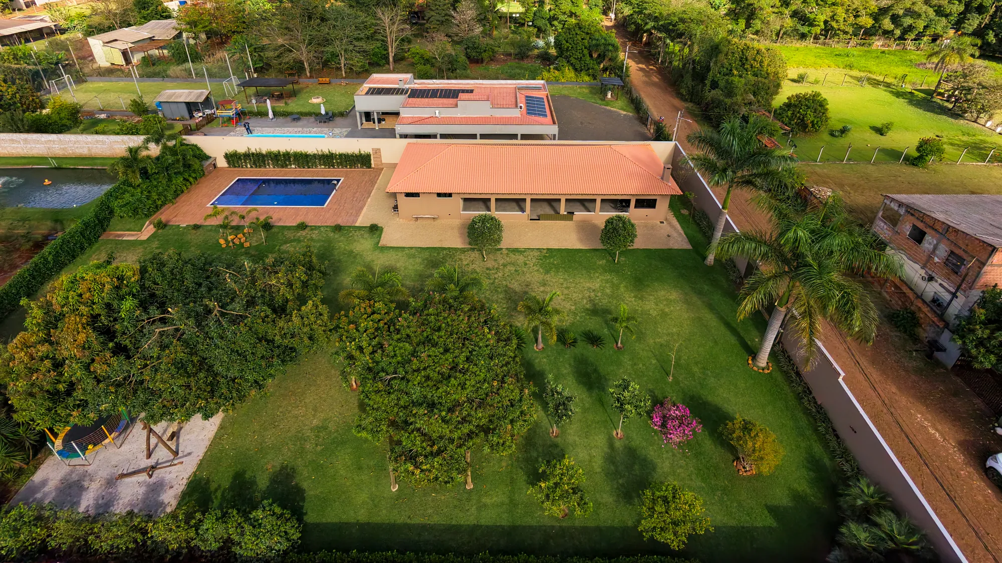 Vista aérea do Recanto Campos: piscina, salão de festas com área gourmet, gramado com pomar e playground