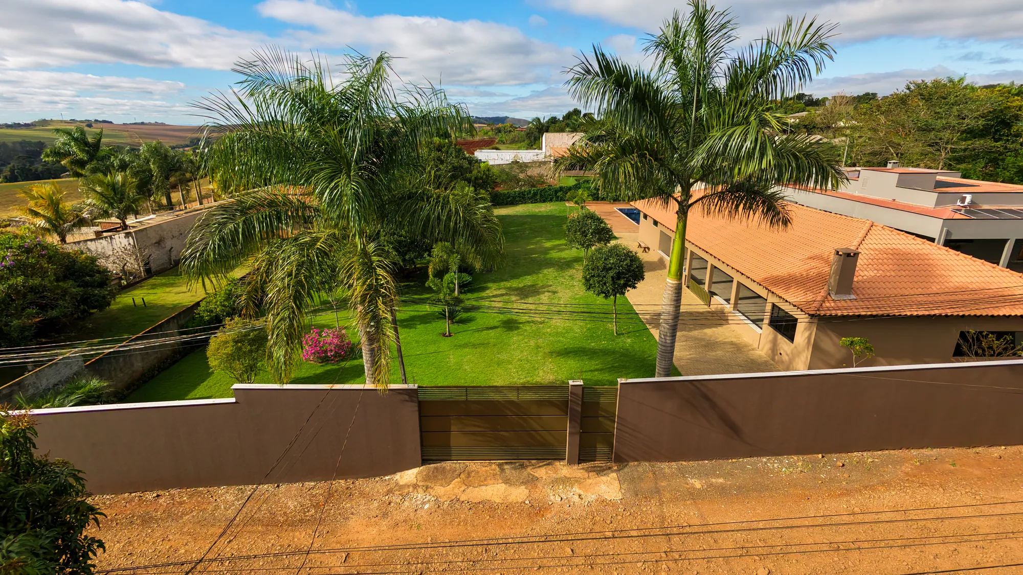 Fachada do Recanto Campos com muro, portão e palmeiras
